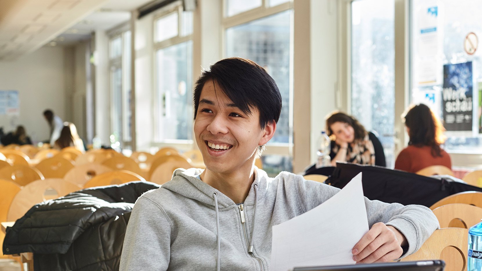 Junger Student aus Asien sitzt an einem Tisch und arbeitet