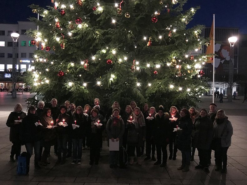 Beschäftigte der Hochschule Mainz vor dem geschmückten Weihnachtsbaum auf dem Weihnachtsmarkt in Mainz