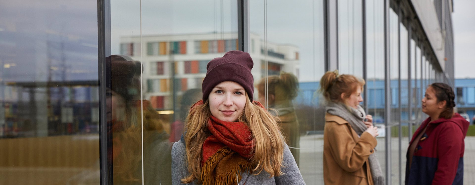 Studierende lehnen an der Glasfront zur Bibliothek